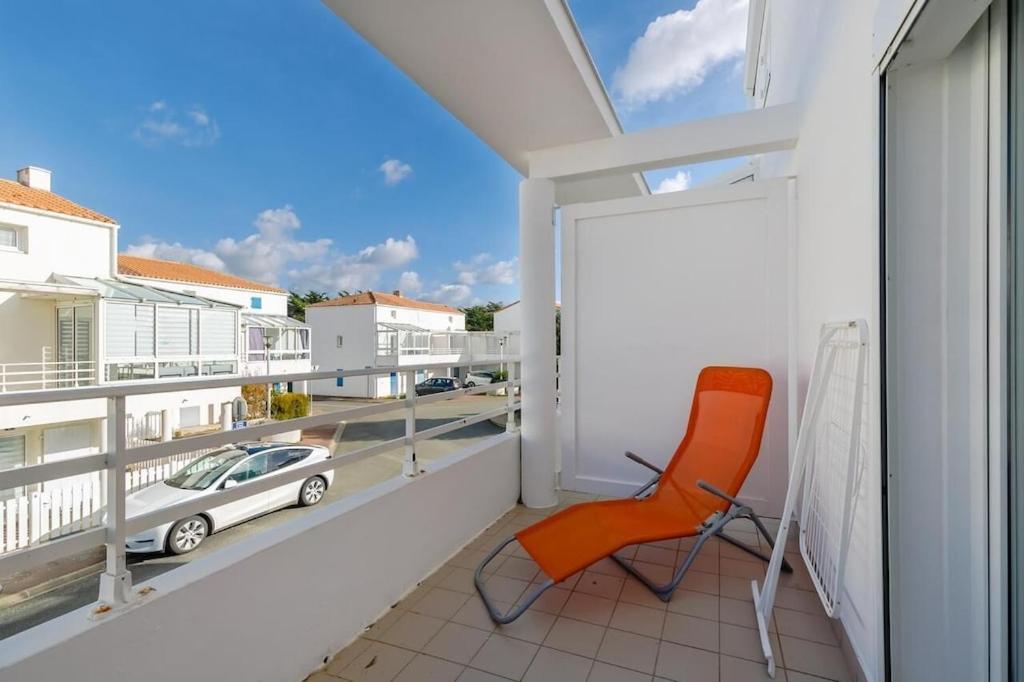 une chaise orange assise sur un balcon avec vue sur une voiture dans l'établissement LA ROSE DE L OCEAN, à Saint-Hilaire-de-Riez