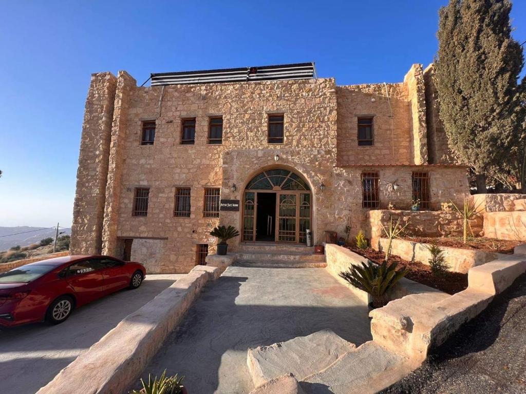 a red car parked in front of a stone building at Petra fort hotel in Wadi Musa