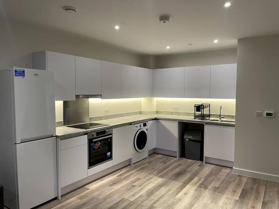 a kitchen with white cabinets and a washer and dryer at Beautiful one-bed in White City! in London