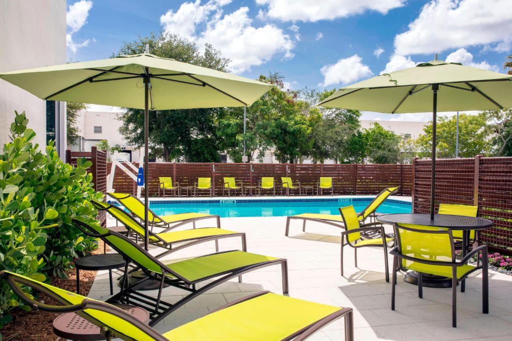 een patio met tafels en stoelen, parasols en een zwembad bij SpringHill Suites by Marriott Miami Doral in Miami