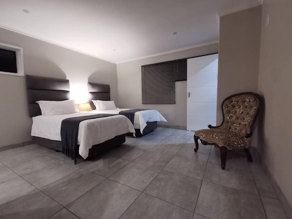 a hotel room with two beds and a chair at Stay@603 Guesthouse in Pretoria