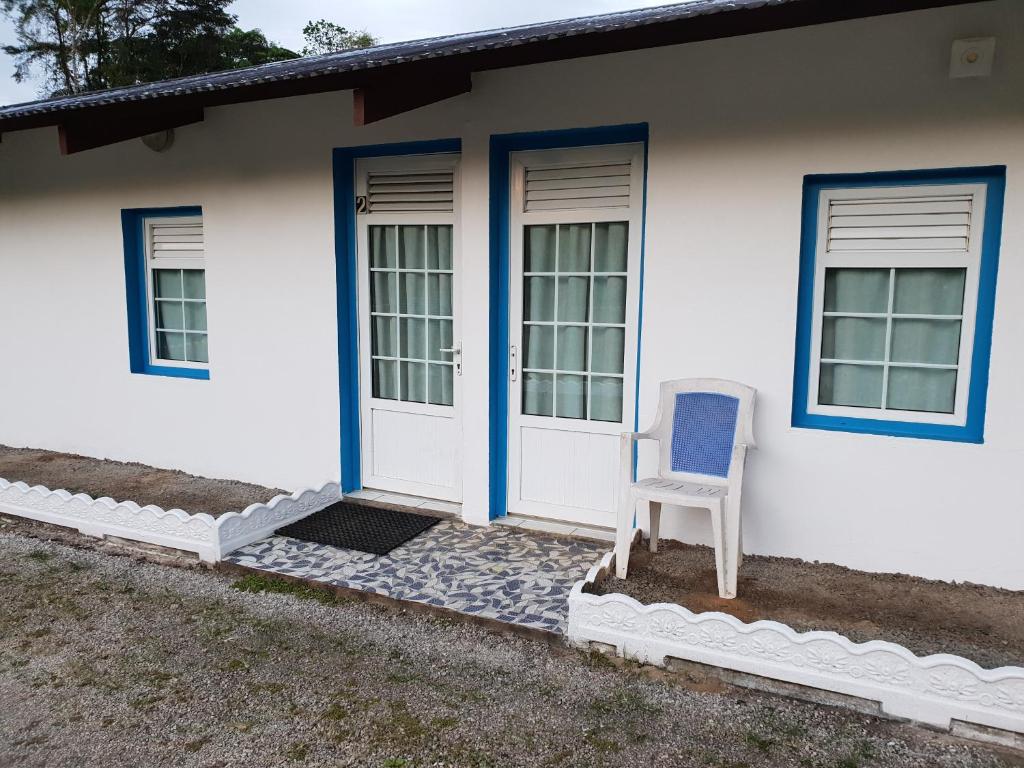 une chaise bleue assise à l'extérieur d'une maison blanche dans l'établissement RESIDENCE VERO, à Matoury
