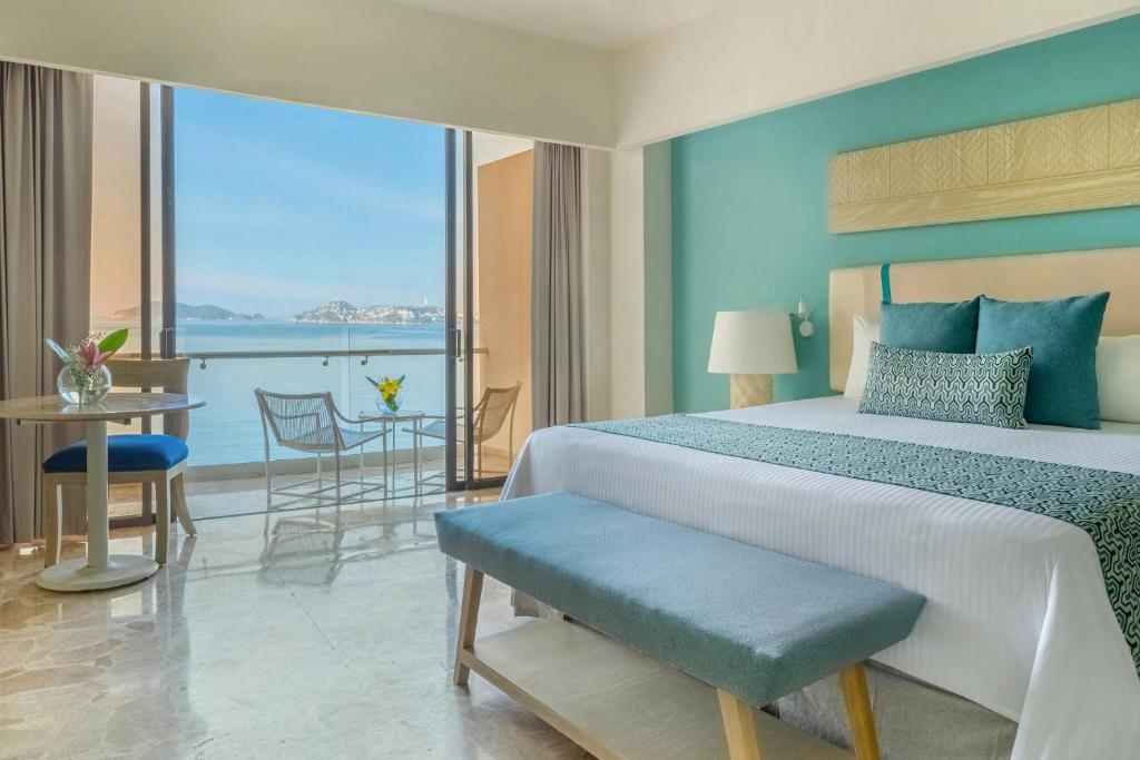 a bedroom with a bed and a view of the ocean at Dreams Acapulco in Acapulco