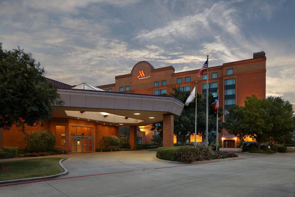 un edificio de hotel con una bandera americana delante de él en Marriott DFW Airport South, en Fort Worth