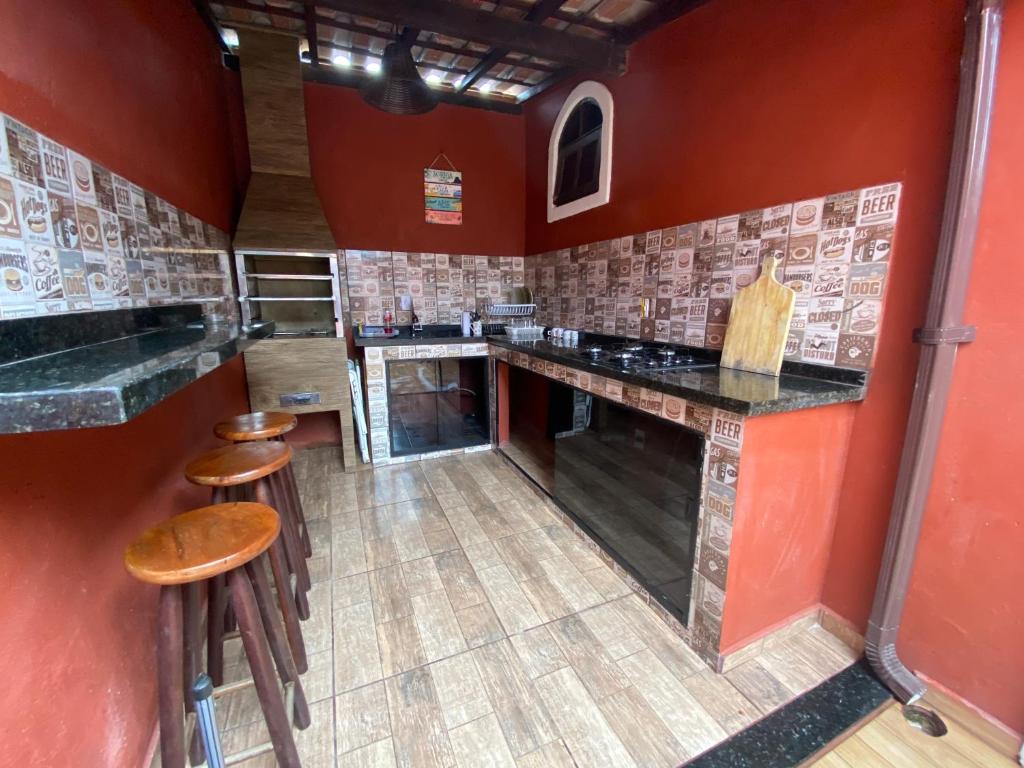 a kitchen with red walls and wooden stools at Casa Sole & Mare - Praias e Cachoeiras in Paraty