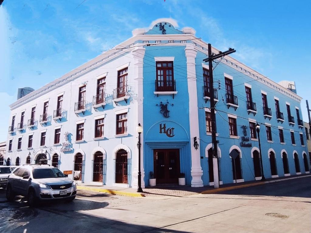 un bâtiment bleu et blanc avec une voiture garée devant dans l'établissement HOTEL COLONIAL MATAMOROS, à Matamoros