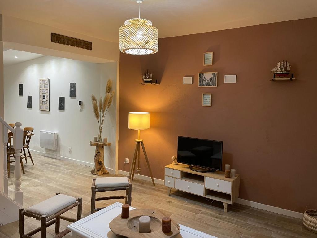 een woonkamer met een televisie en een tafel bij Gîte du Damier in Saint-Valery-sur-Somme