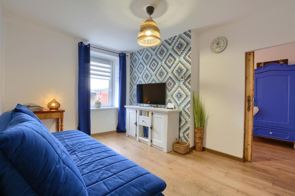 a living room with a blue couch and a tv at Apartament Pod Jałowcem Góry Sowie 533-543-732 in Jedlina-Zdrój