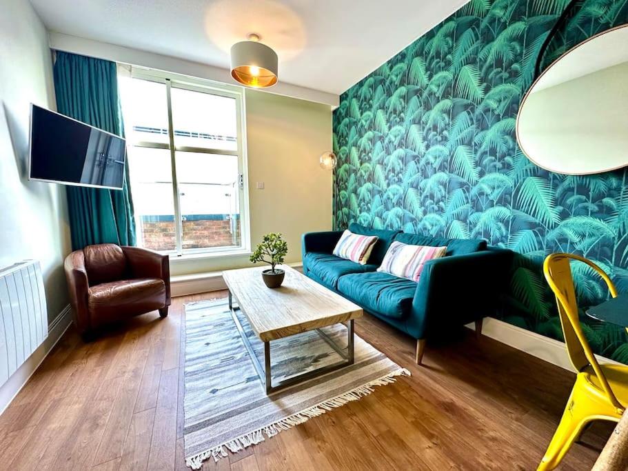 a living room with a blue couch and a green wall at Amazing Modern Apartment - Free Secure Parking! - 1 Minute walk to Poole Quay - Great Location - Free Parking - Fast WiFi - Smart TV - Newly decorated - sleeps up to 2! Close to Poole & Bournemouth & Sandbanks in Poole