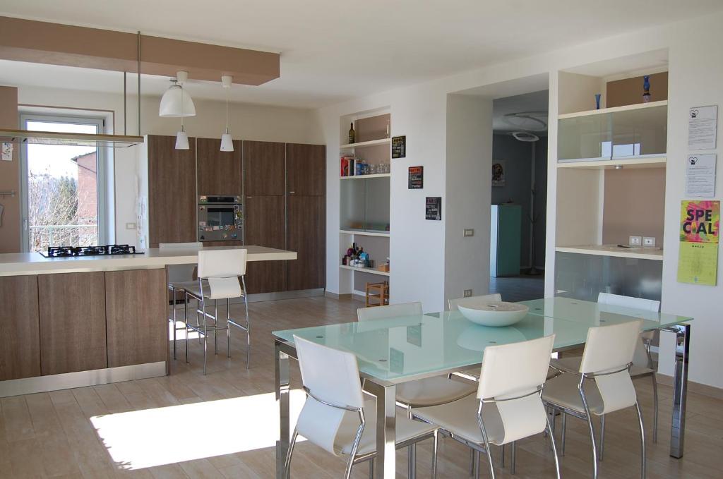 een keuken met een glazen tafel en witte stoelen bij Monferrato Asti-luminosa villa in CastellʼAlfero