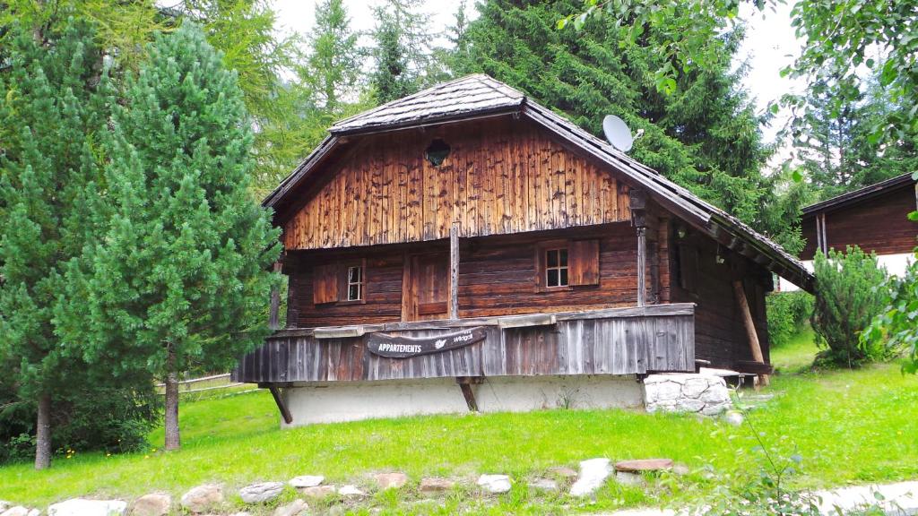 een oud houten huis in een veld met bomen bij Chalet Wildgall in Anterselva di Mezzo