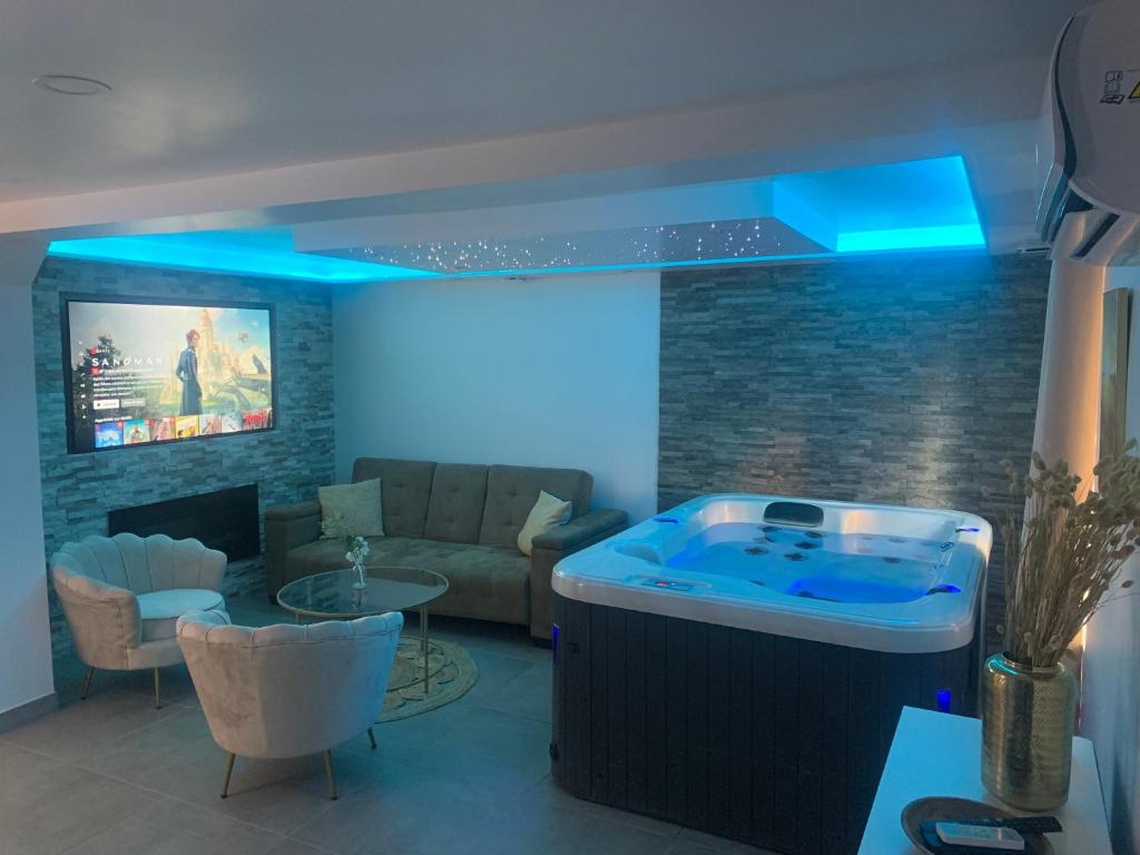 een grote hot tub in een woonkamer met blauwe verlichting bij Sandspa logement avec jacuzzi in Orange