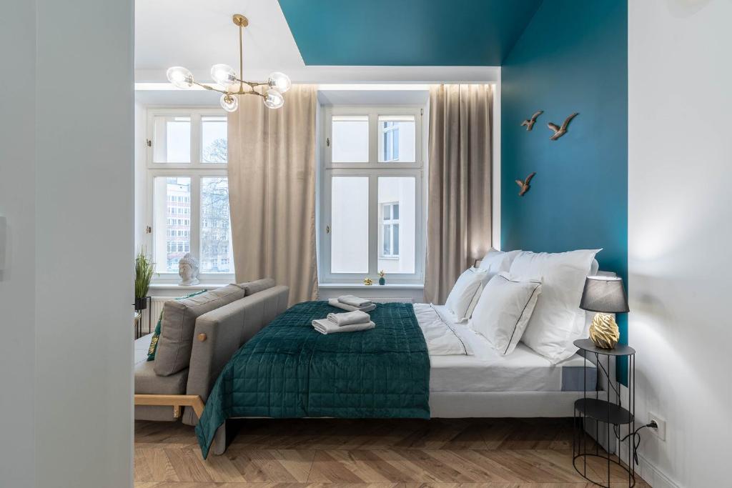 a bedroom with blue walls and a bed and a couch at Golden Circles No.2 in Poznań