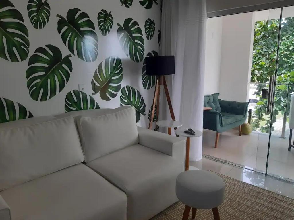 een woonkamer met een witte bank en planten aan de muur bij Apartamento pé na areia in Porto Seguro