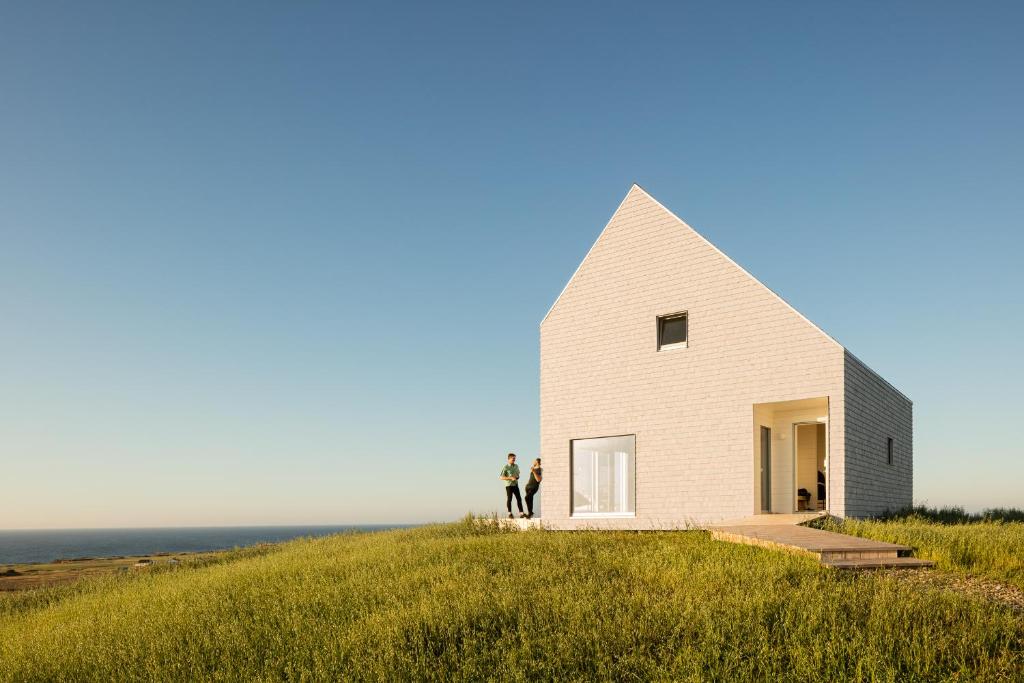 una casa en una colina con dos personas de pie en ella en Les Rochers - Îles de la Madeleine en Havre-Aubert