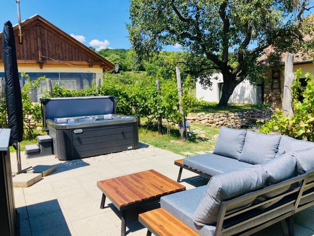 a patio with a couch and a table and a barbecue at Édenkert Vendégházak in Pécsvárad