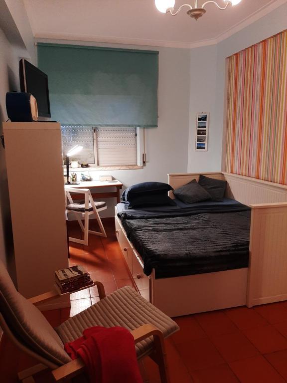 a bedroom with a bed and a desk with a chair at Almadense in Almada