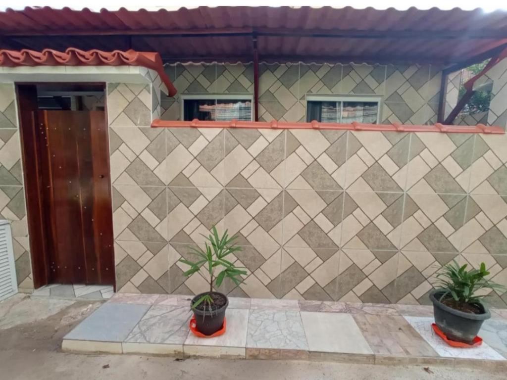 Casa Oliveira's Paquetá في ريو دي جانيرو: منزل به اثنين من النباتات الفخارية أمام الجدار