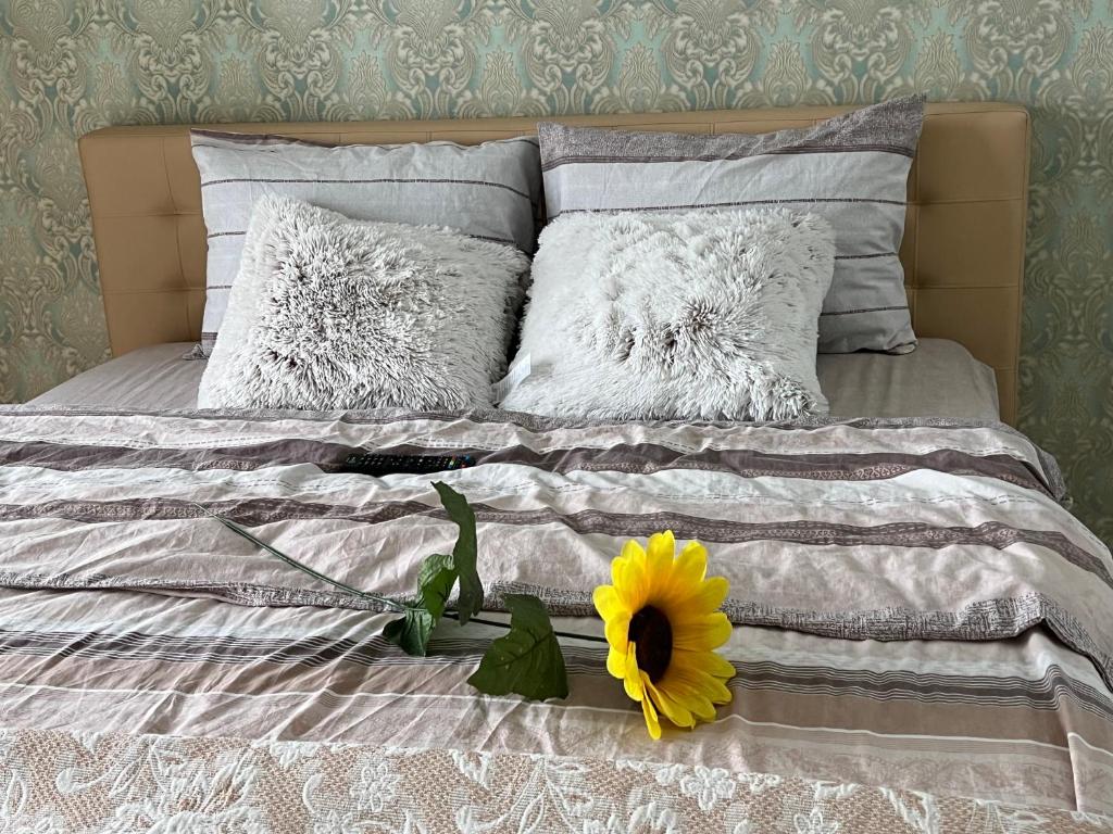 Una cama con dos almohadas y una flor amarilla. en Paris Evening, en Chişinău