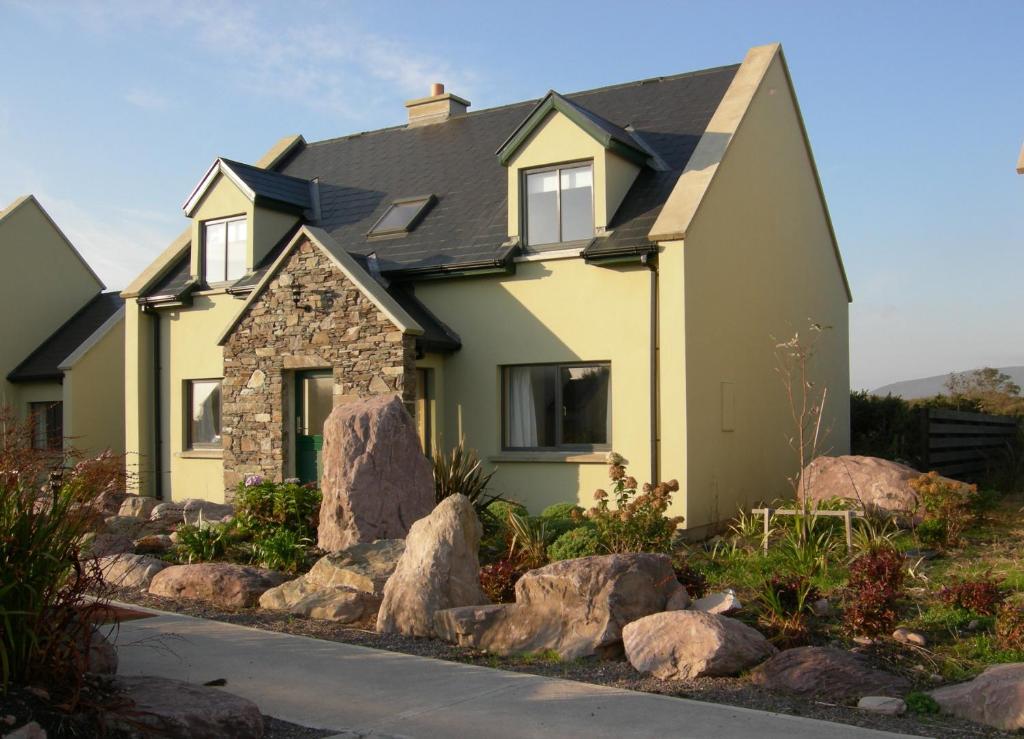 a yellow house with rocks in front of it at Waterville Holiday Homes No 10 in Waterville