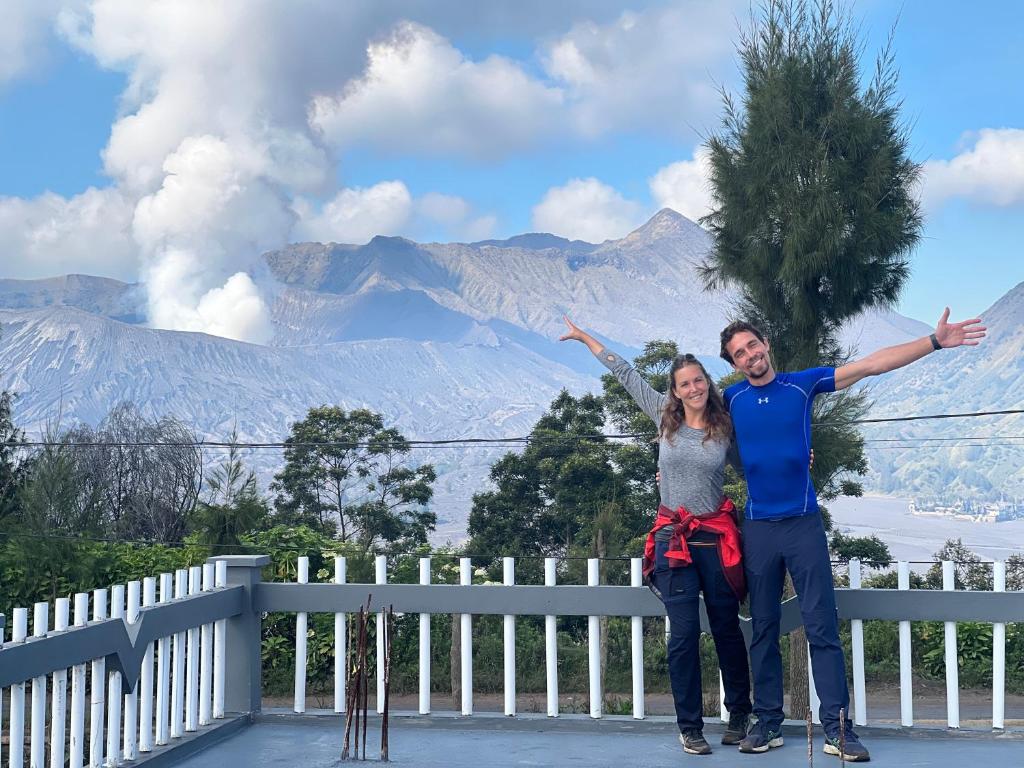 a man and a woman standing in front of a mountain at Cahyo Homestay Bromo in Bromo