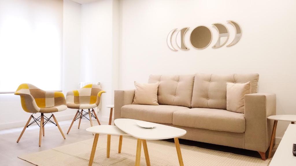 ein Wohnzimmer mit einem Sofa und Stühlen in der Unterkunft Apartamento DENVER - Centro, Nuevo, Diseño, Wifi in Valladolid