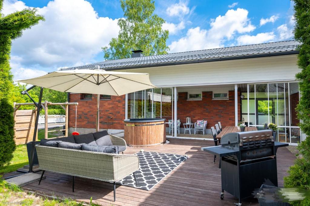 a patio with a couch and an umbrella and a grill at Vantaa Sauna Cottage in Vantaa