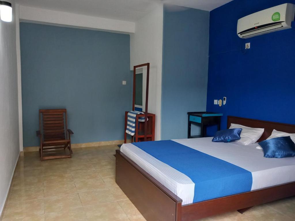 a bedroom with a bed with a blue wall at The Madampa Sea Side Lodge in Ambalangoda