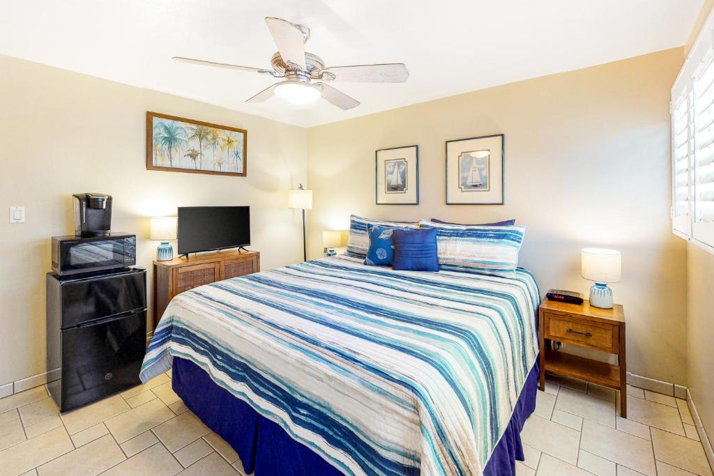 a bedroom with a bed and a flat screen tv at Island Surf 601A in Kihei