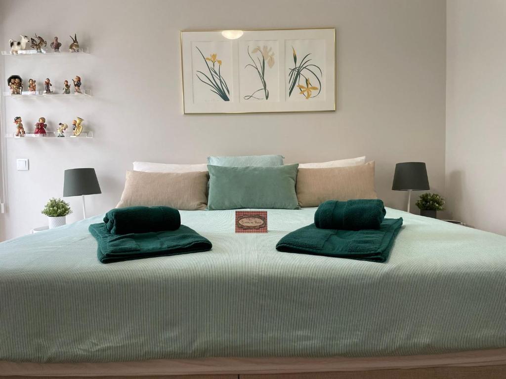 a large bed with two green pillows on it at Casa de Cece in Lagoa