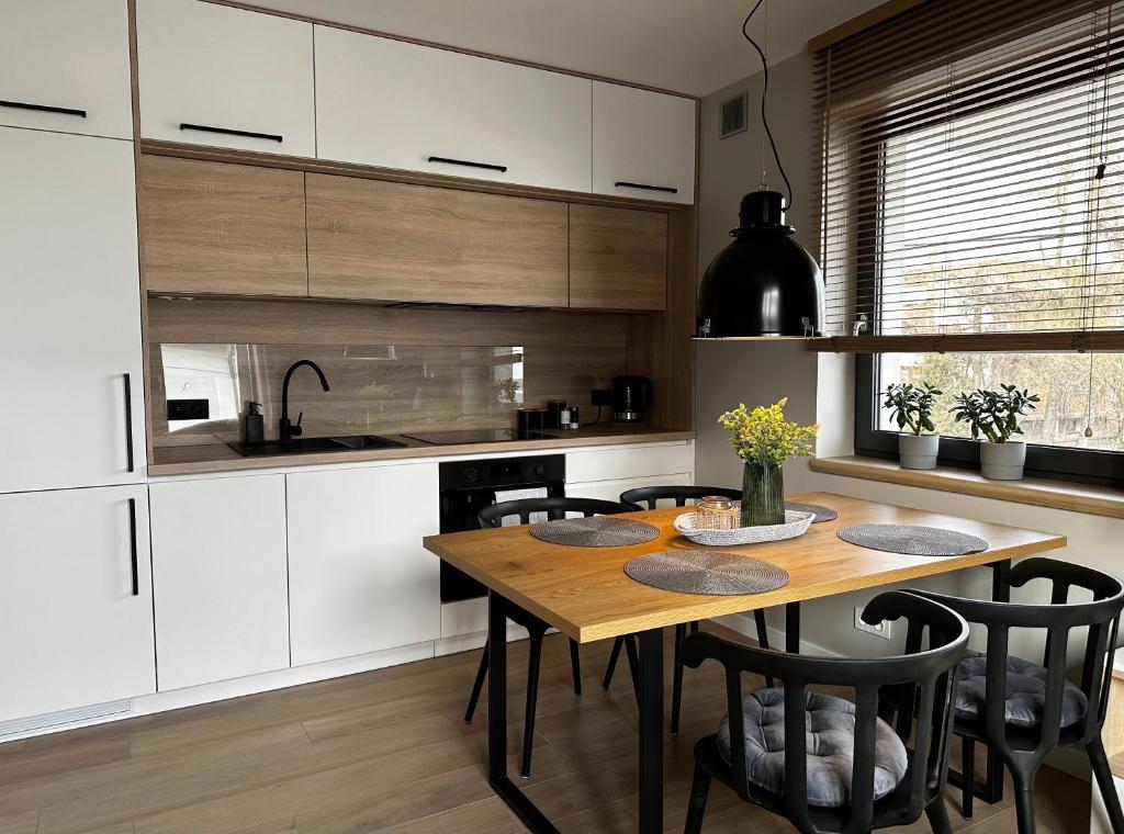 a kitchen with a wooden table and black chairs at Apartament Pod Ojcowem in Skała
