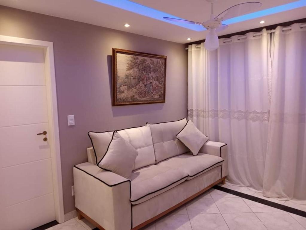 ein Wohnzimmer mit einem Sofa und einem Deckenventilator in der Unterkunft Apartamento CABO FRIO - PRAIA DO FORTE in Cabo Frio