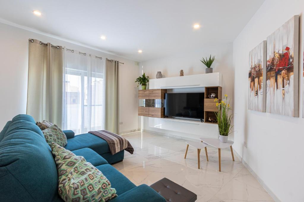ein Wohnzimmer mit einem blauen Sofa und einem TV in der Unterkunft H2 -Modern and Spacious 3 Bedroom Apartment in San Ġwann