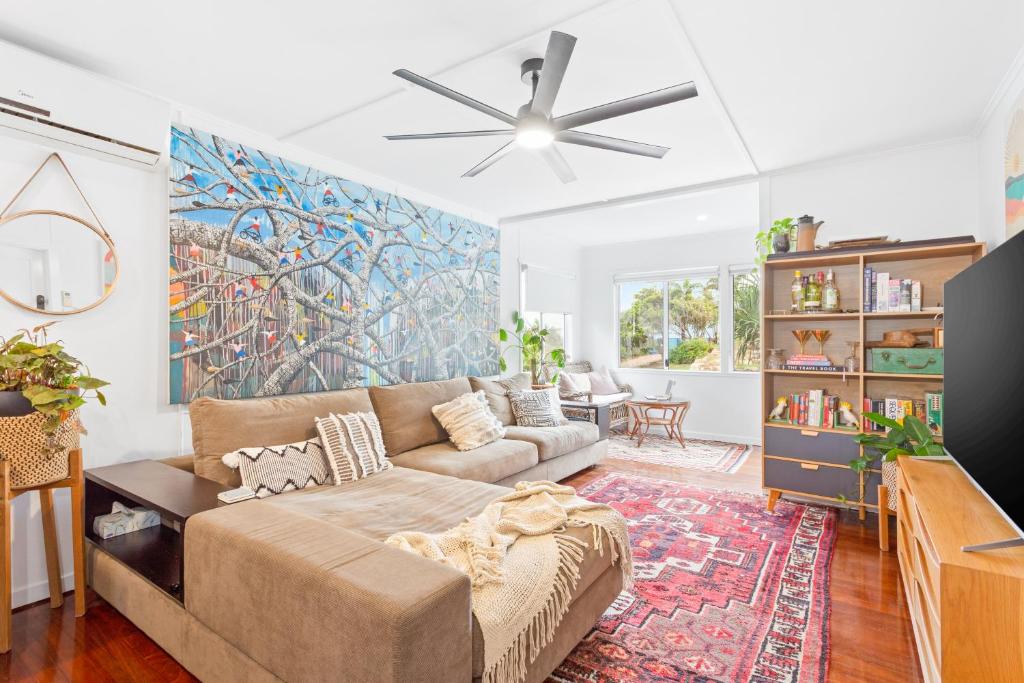 a living room with a couch and a ceiling fan at Cooee Bay Beach House in Yeppoon