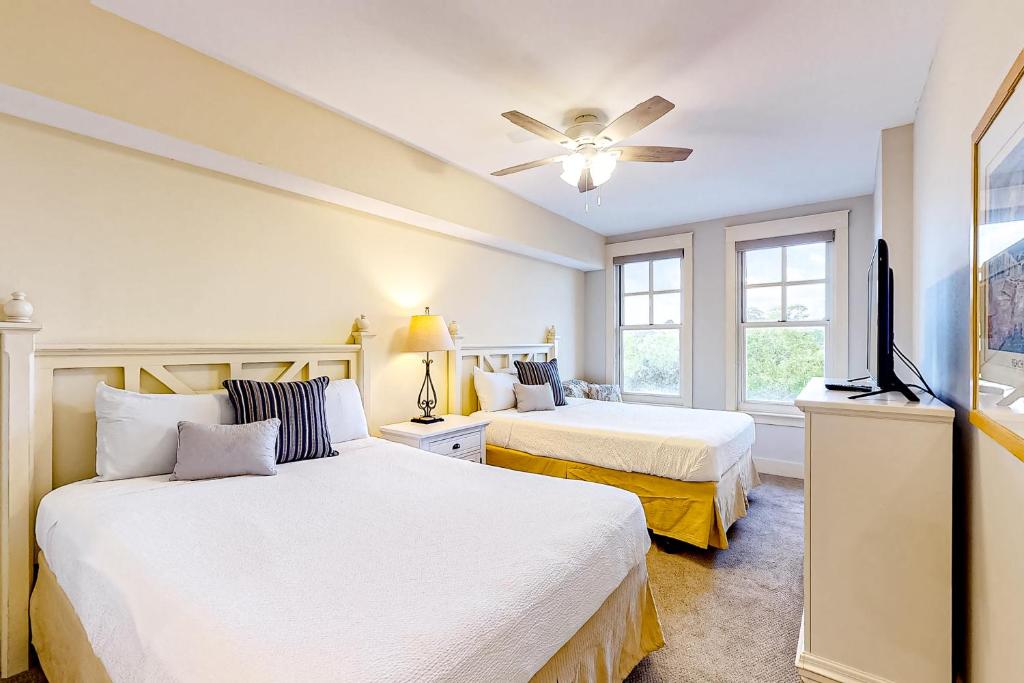 a bedroom with two beds and a flat screen tv at Baytowne Wharf - Observation Point North #460 in Destin