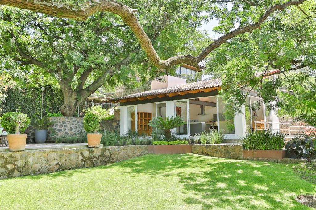 a house with a stone retaining wall and a yard at Casa MALI con alberca. in Malinalco