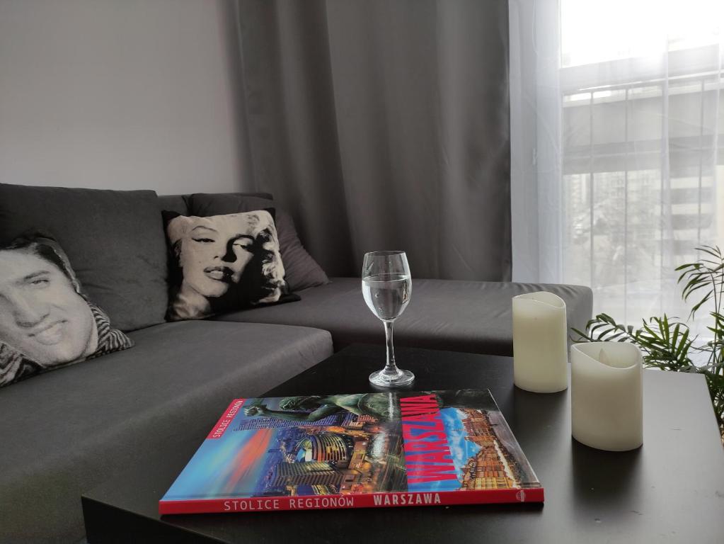 uma sala de estar com um sofá e uma mesa com um livro em Apartament Rondo ONZ em Varsóvia