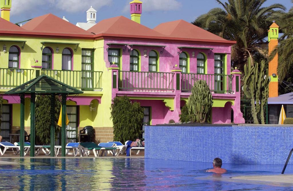 a man swimming in a swimming pool in front of a building at eó Maspalomas Resort in Maspalomas