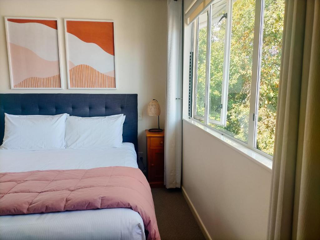 a bedroom with a bed and two windows at Boutique Motel in Nelson