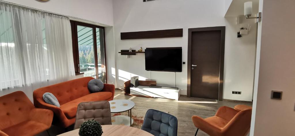 a living room with orange furniture and a flat screen tv at Forest View Silver M B34 Poiana Brasov in Poiana Brasov