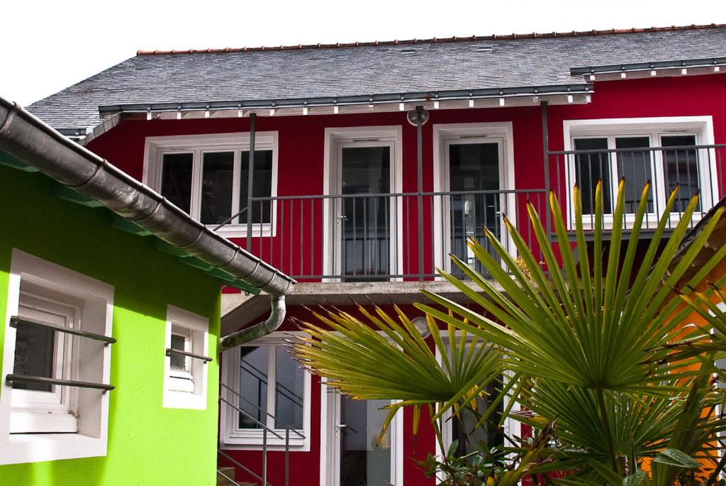 un bâtiment rouge et vert avec des palmiers devant lui dans l'établissement La Compagnie des 5 Mondes, à Saint-Nazaire