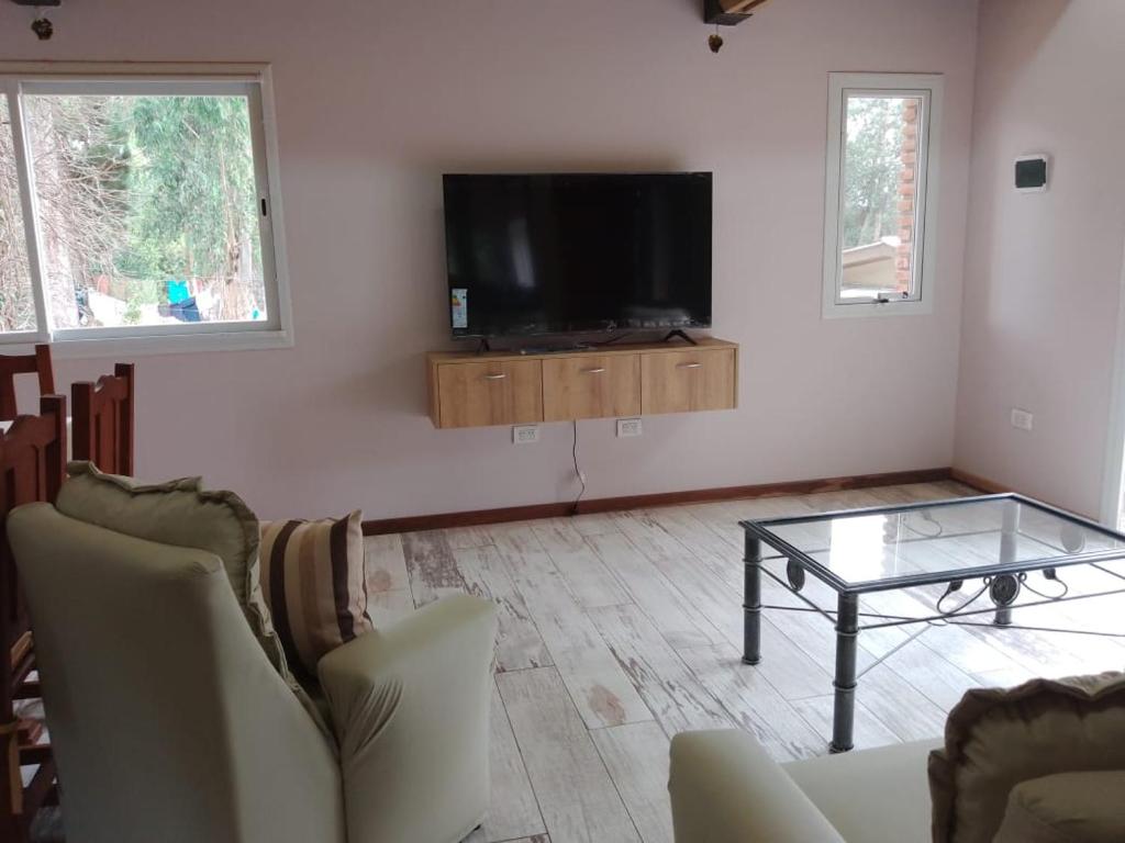 a living room with a tv and a glass table at Cielo de sierra in Sierra de los Padres