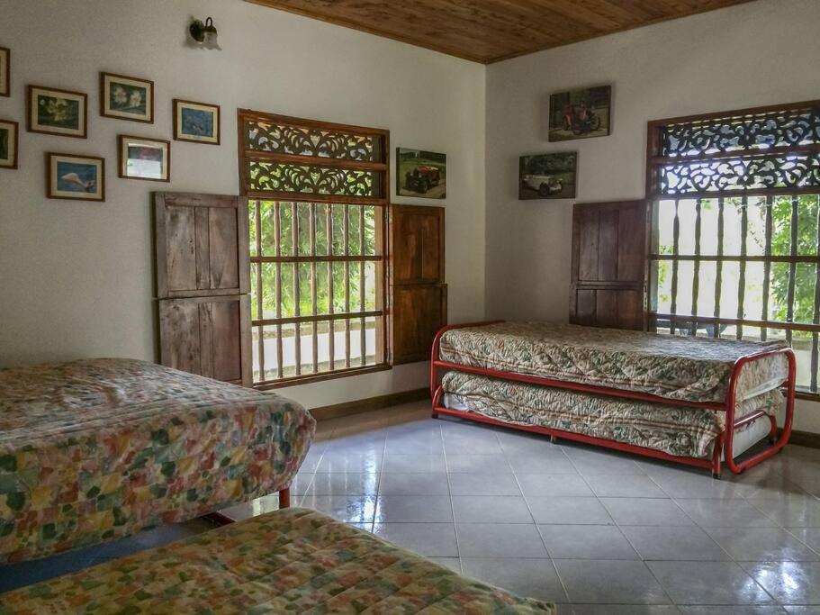 Cette chambre comprend 2 lits et 2 fenêtres. dans l'établissement Finca Maria Paula. El Paraiso, encantadora finca en Doradal Antioquia, à Doradal