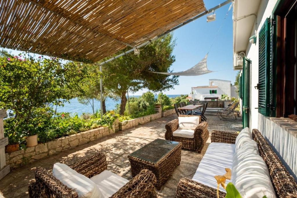 un patio con muebles de ratán y vistas al agua en Artemisia Homes - Villa Cristina al Mare, en Marina Porto