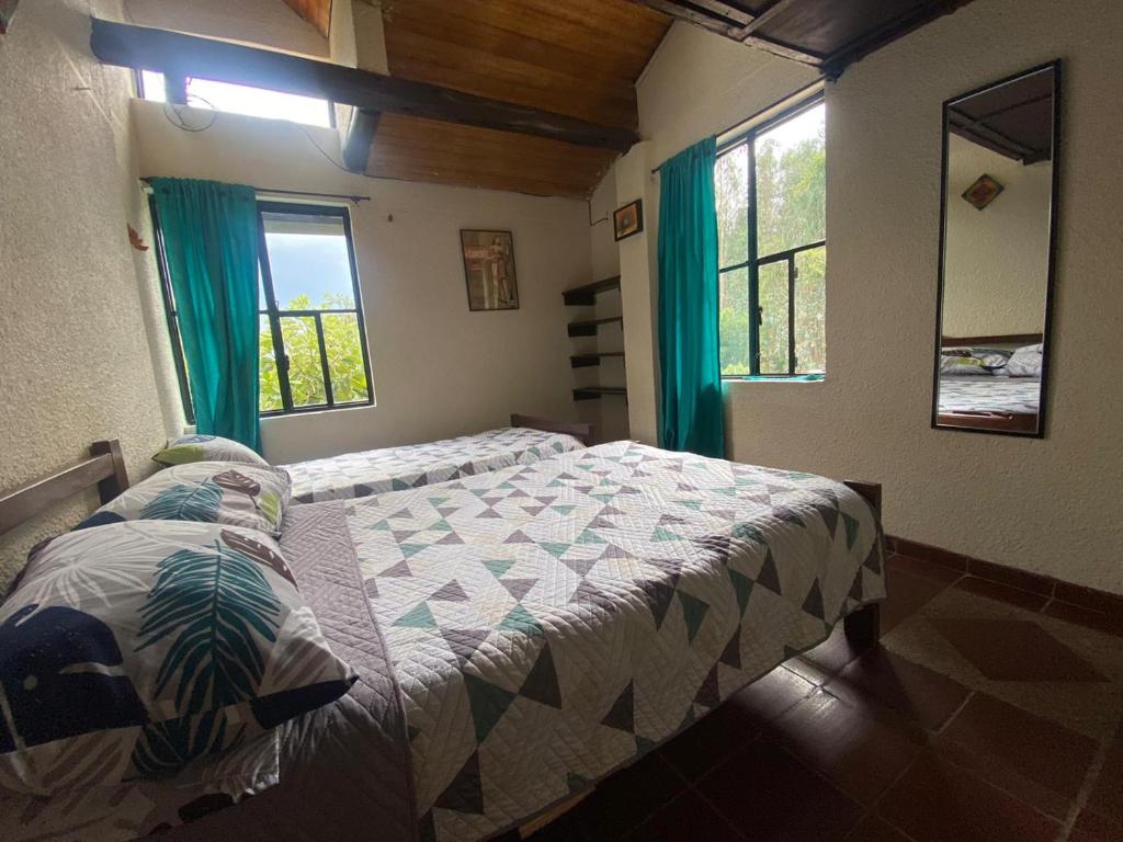 a bedroom with a bed and two windows at Arte sin Fronteras Hostel in Paipa