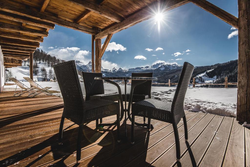 a table and chairs on a deck with a view of the mountains at Appartements Chalet Bandiarac in San Cassiano
