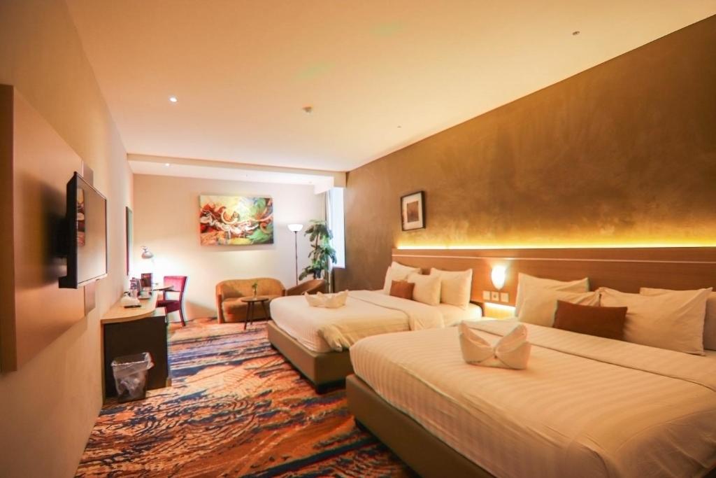 ジョグジャカルタにあるDe Laxston Hotel Yogyakarta, Azana Hotels Collectionのベッド2台とソファがあるホテルの部屋