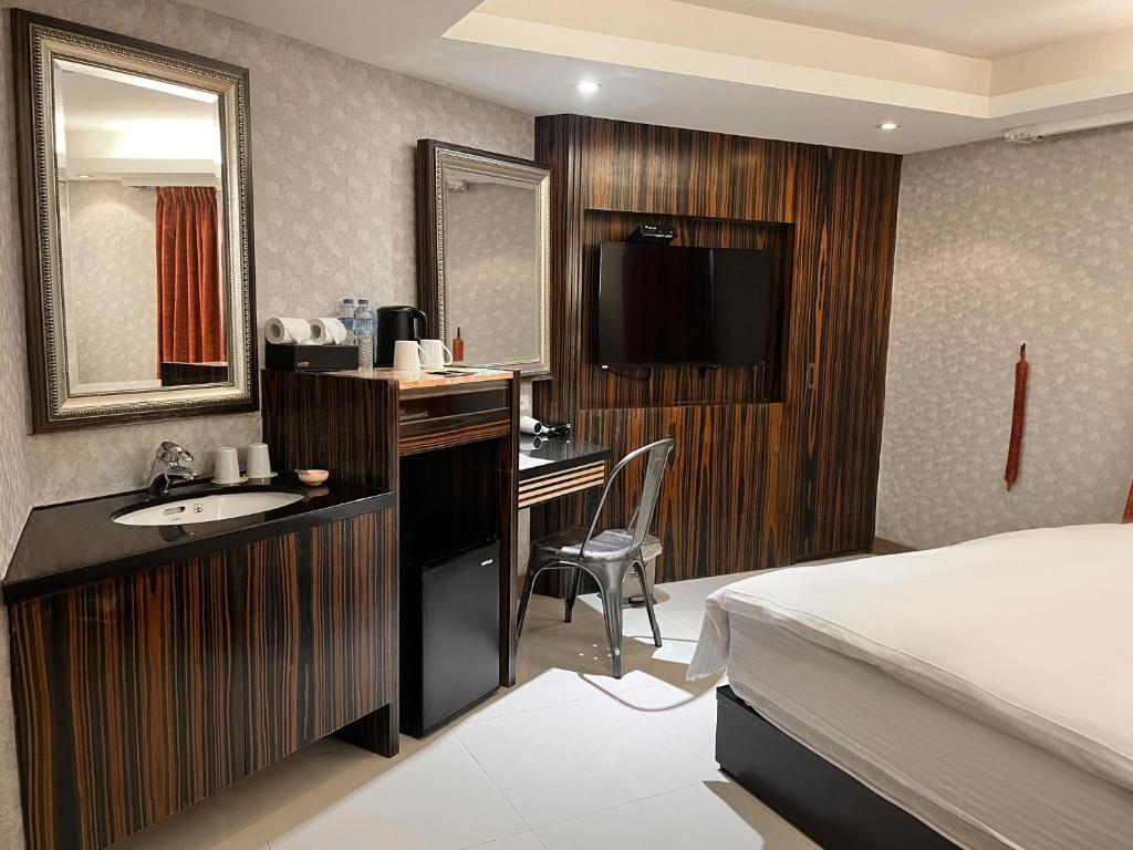 a hotel room with a bed and a desk and a sink at Guide Hotel Taipei Xinyi in Taipei