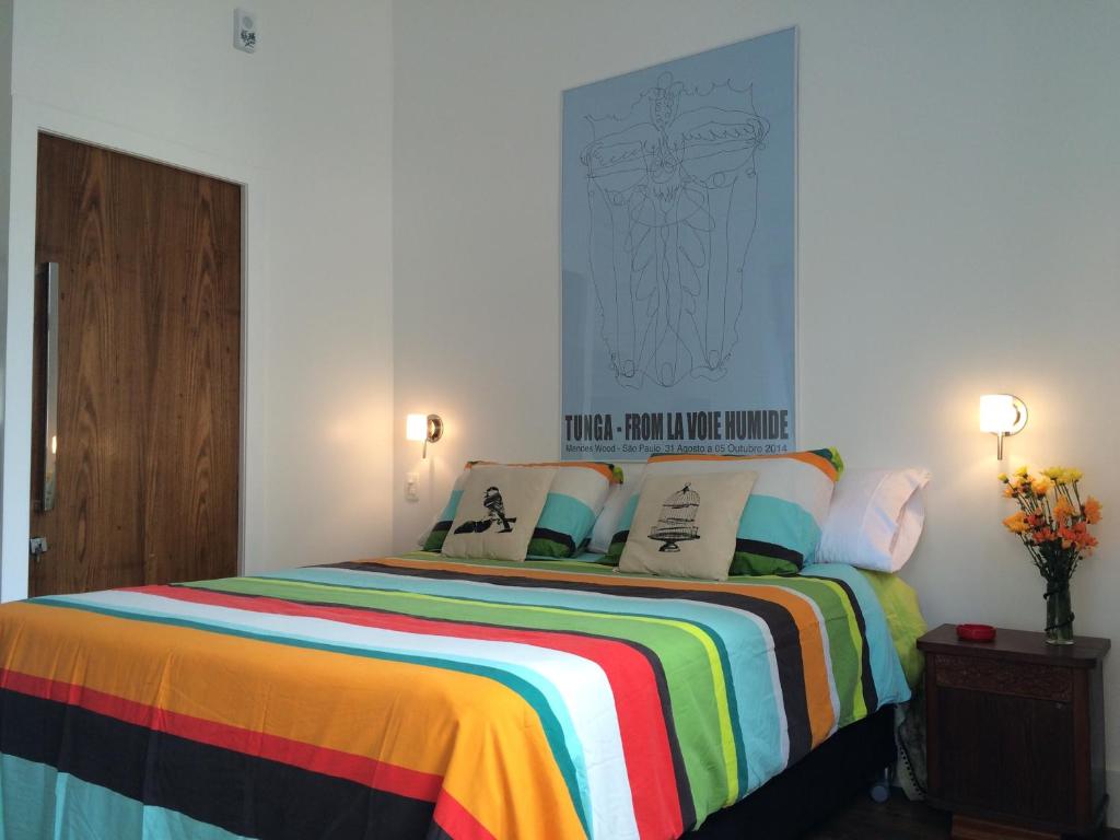 Studio Rio Beira Mar في ريو دي جانيرو: غرفة نوم مع سرير وبطانية ملونة