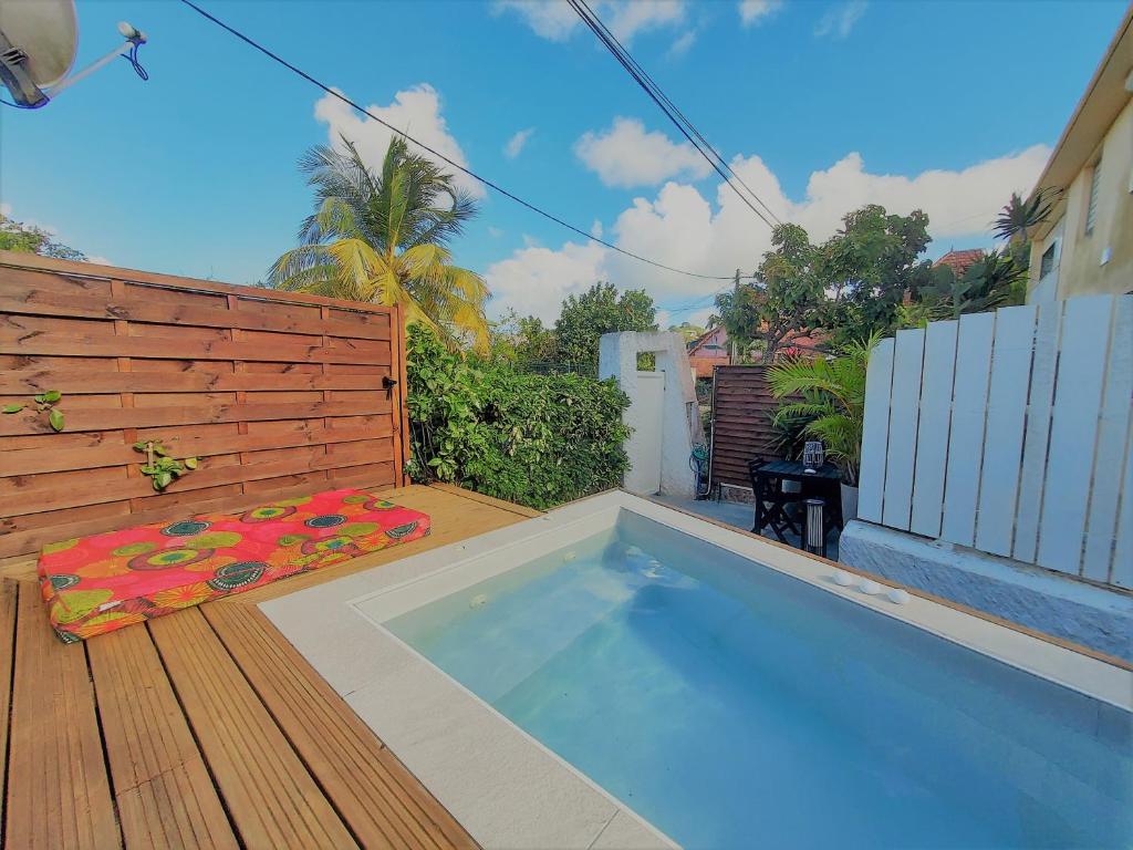 a swimming pool in a backyard with a wooden deck at Ocean BAYALOCATION in LʼAnse Mitan